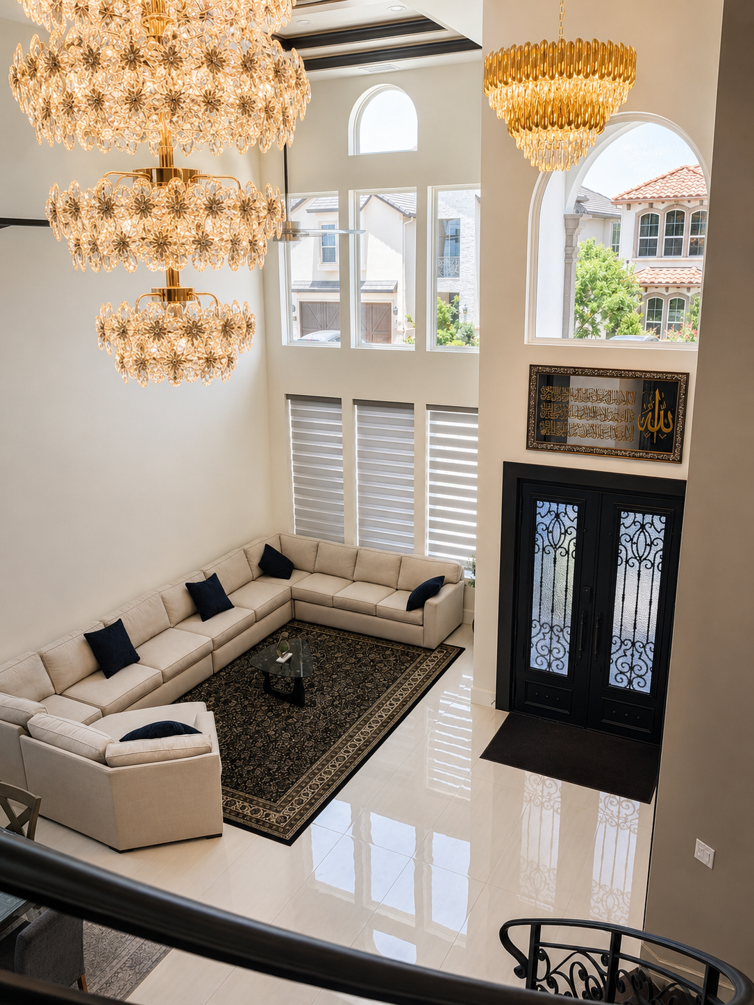 Double-height living room with crystal chandeliers, black double doors, and cream seating