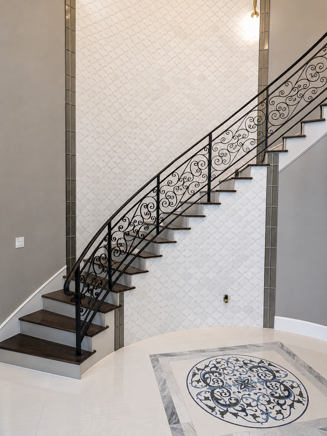 Curved custom staircase with black wrought-iron railing and patterned tile floor